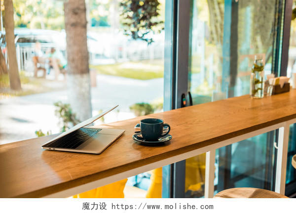 木制咖啡厅柜台的笔记本电脑和咖啡杯